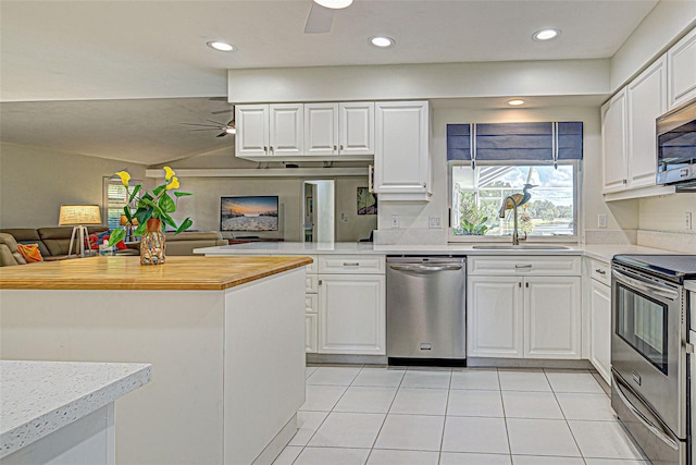 kitchen with kitchen peninsula, white cabinets, appliances with stainless steel finishes, light tile patterned flooring, and sink