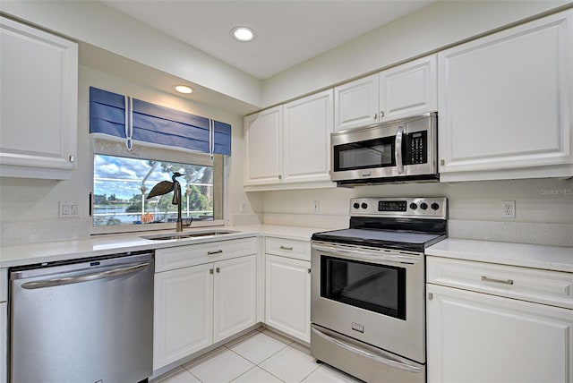 kitchen with light tile patterned flooring, white cabinets, stainless steel appliances, and sink