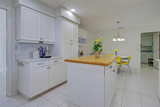 kitchen with light tile patterned flooring, pendant lighting, a kitchen island, and white cabinets