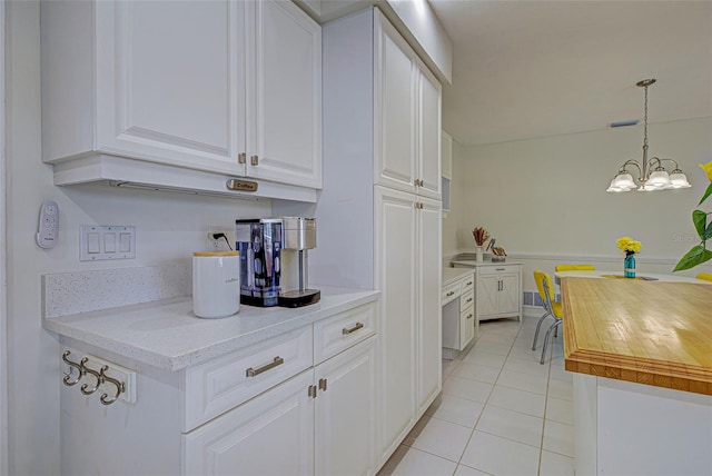 kitchen featuring decorative light fixtures, white cabinets, light stone counters, a notable chandelier, and light tile patterned floors