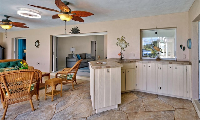 kitchen featuring kitchen peninsula, white cabinets, sink, and ceiling fan