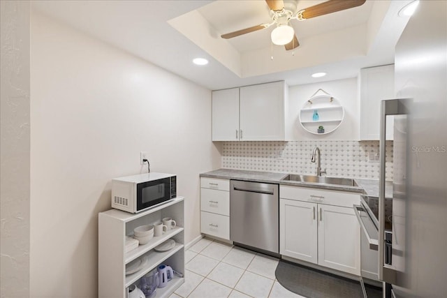 kitchen featuring white cabinets, a tray ceiling, sink, and stainless steel dishwasher