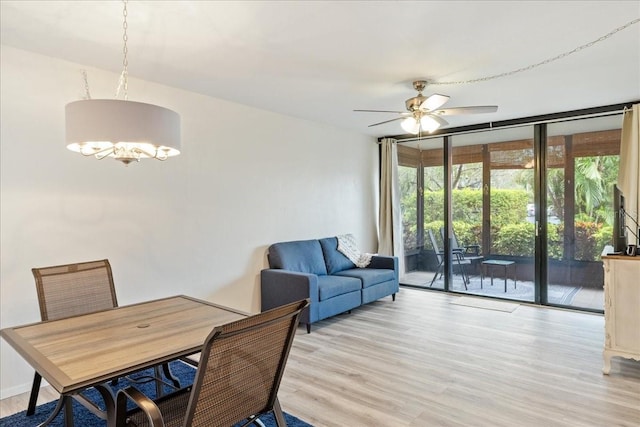 dining space featuring ceiling fan with notable chandelier and light wood-type flooring