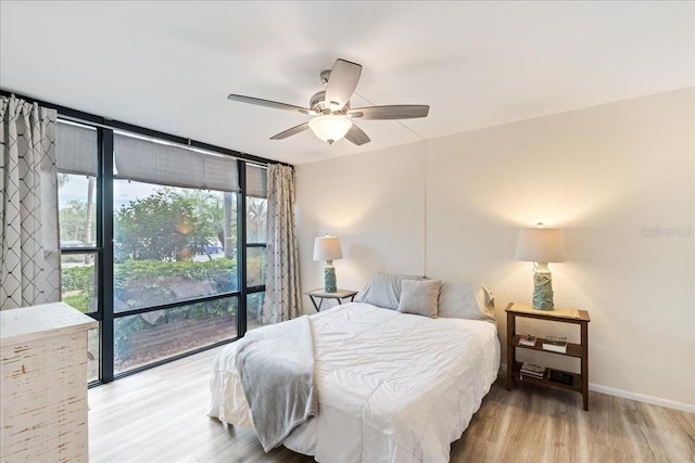 bedroom with light hardwood / wood-style floors, ceiling fan, and expansive windows