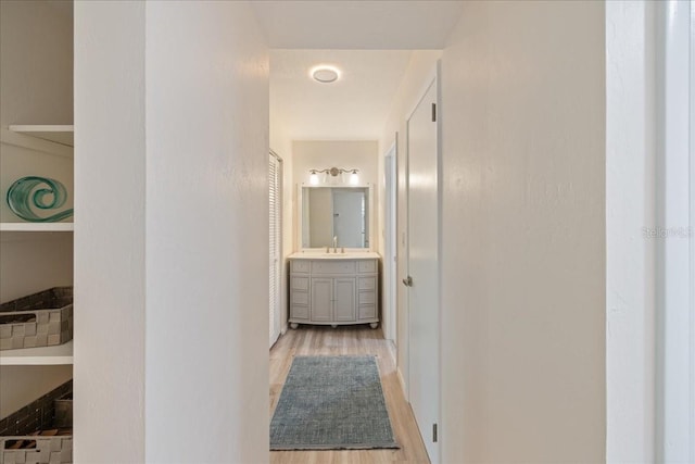 hallway with light wood-type flooring and sink