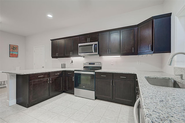 kitchen featuring dark brown cabinetry, light stone countertops, sink, kitchen peninsula, and appliances with stainless steel finishes