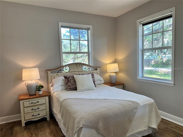 bedroom with dark hardwood / wood-style floors and multiple windows