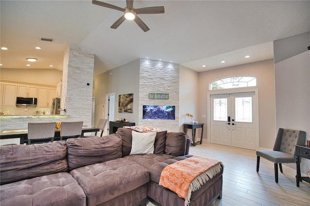 living room with light hardwood / wood-style flooring, ceiling fan, and high vaulted ceiling