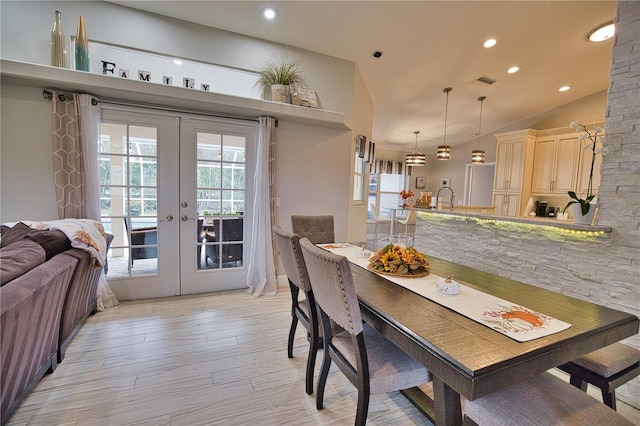 dining room with light hardwood / wood-style flooring, vaulted ceiling, and french doors