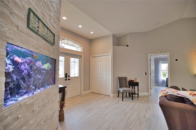 entryway featuring a textured ceiling, light hardwood / wood-style floors, high vaulted ceiling, and a wealth of natural light