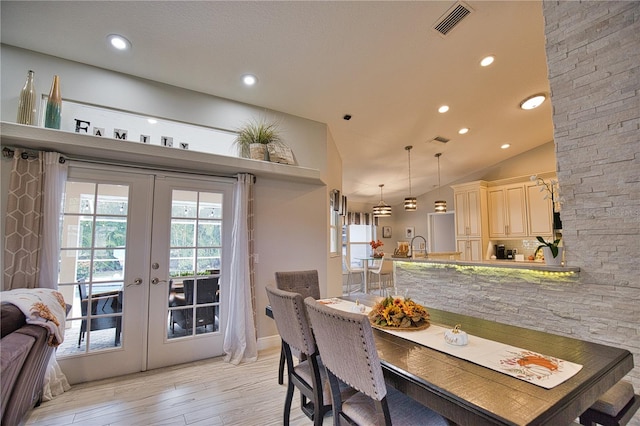 dining space featuring lofted ceiling, light hardwood / wood-style flooring, and french doors