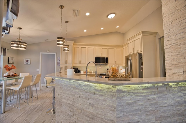 kitchen featuring decorative backsplash, vaulted ceiling, stainless steel appliances, light hardwood / wood-style flooring, and decorative light fixtures