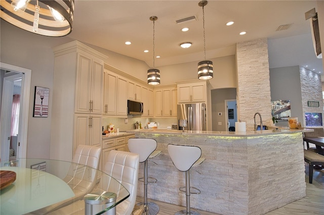 kitchen featuring light hardwood / wood-style flooring, stainless steel appliances, light stone counters, and hanging light fixtures