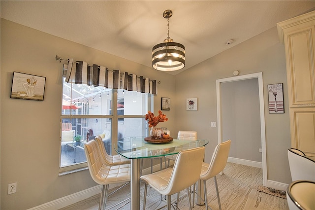 dining room featuring an inviting chandelier, light wood-type flooring, and vaulted ceiling