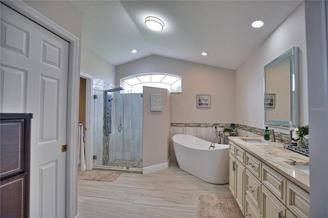 bathroom with a textured ceiling, hardwood / wood-style flooring, vaulted ceiling, separate shower and tub, and vanity