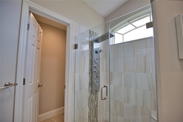 bathroom with a shower with door and hardwood / wood-style floors