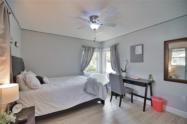 bedroom with ceiling fan, light hardwood / wood-style floors, and multiple windows