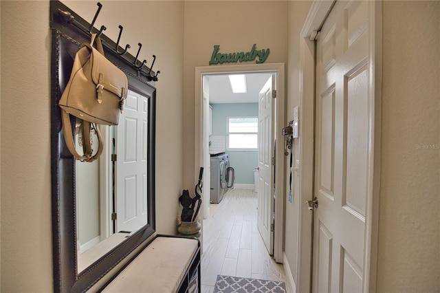 hall with light wood-type flooring and washer and dryer