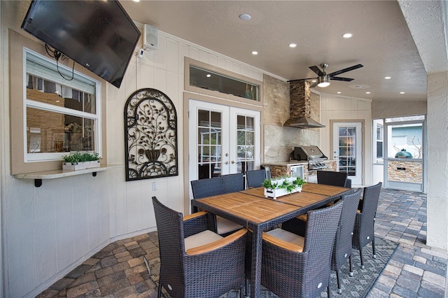 dining space with a textured ceiling, wooden walls, ceiling fan, and french doors