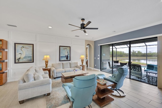 living room with light wood-type flooring, ornamental molding, and ceiling fan