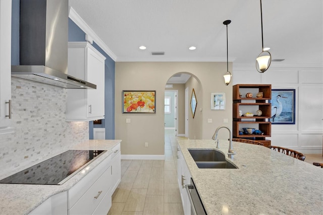 kitchen featuring light stone counters, wall chimney exhaust hood, sink, and white cabinetry