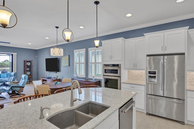 kitchen featuring light stone counters, white cabinets, sink, decorative light fixtures, and stainless steel appliances