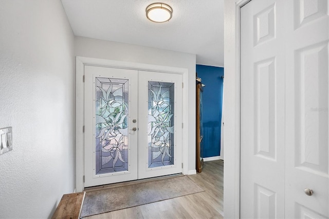 entryway featuring light wood-type flooring, a textured ceiling, and french doors