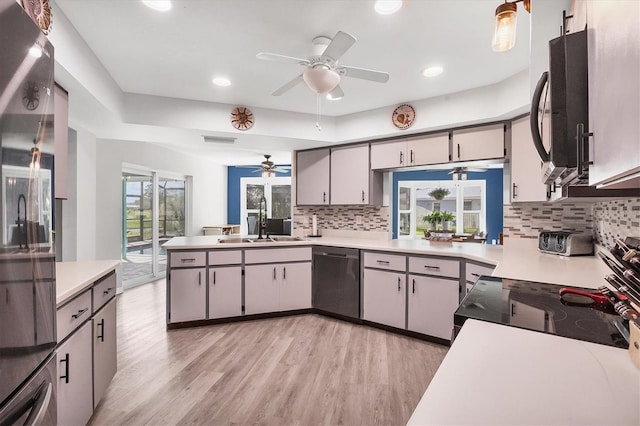 kitchen with sink, gray cabinetry, stainless steel dishwasher, light hardwood / wood-style flooring, and backsplash