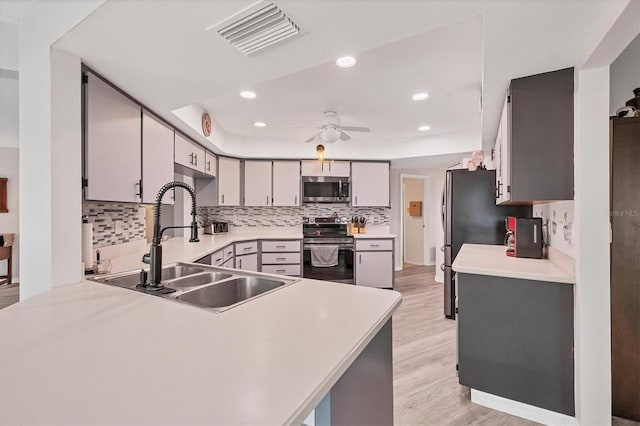 kitchen with decorative backsplash, kitchen peninsula, stainless steel appliances, light hardwood / wood-style flooring, and sink