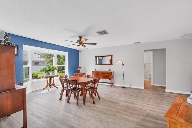 dining space with a textured ceiling, light hardwood / wood-style floors, and ceiling fan