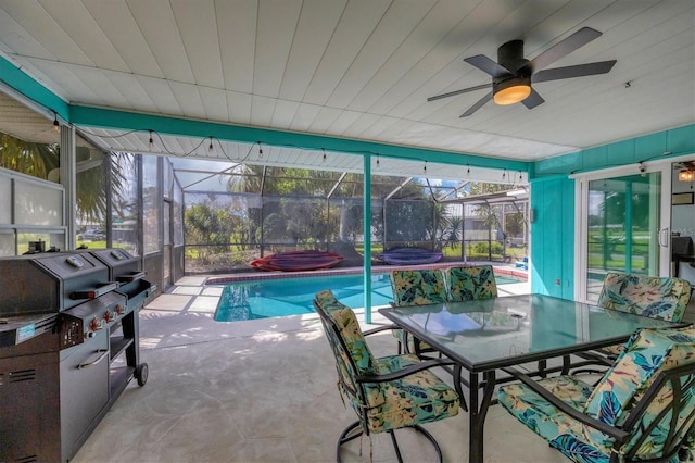 view of swimming pool with ceiling fan, glass enclosure, and a patio