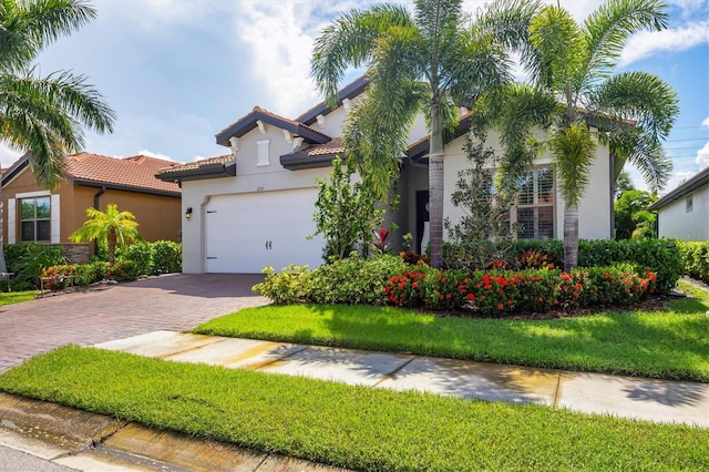 mediterranean / spanish home featuring a garage and a front lawn