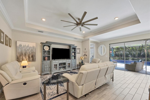 living room featuring ornamental molding, light wood-type flooring, and a tray ceiling