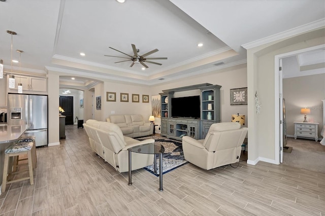 living room featuring light hardwood / wood-style flooring, a tray ceiling, ceiling fan, and ornamental molding