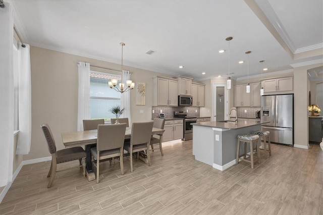 kitchen with a breakfast bar, pendant lighting, stainless steel appliances, crown molding, and a kitchen island with sink