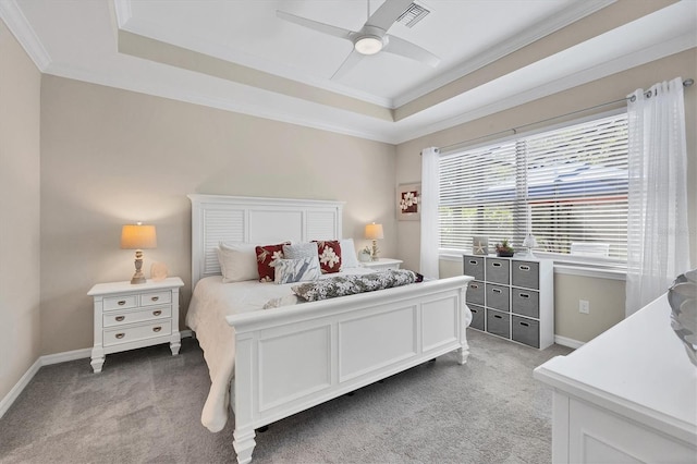 bedroom featuring crown molding, a tray ceiling, light carpet, and ceiling fan