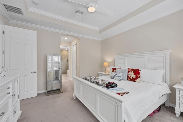 carpeted bedroom with ceiling fan, a tray ceiling, and crown molding