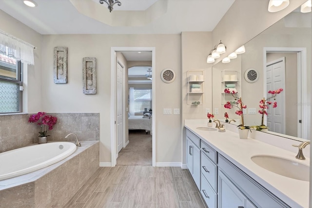 bathroom featuring wood-type flooring, tiled tub, and vanity