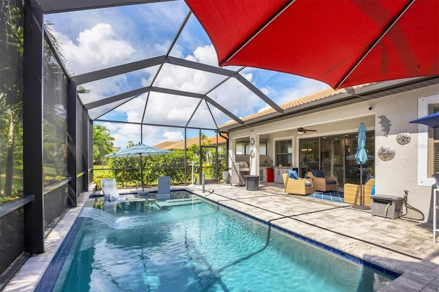 view of swimming pool with glass enclosure, ceiling fan, pool water feature, and a patio