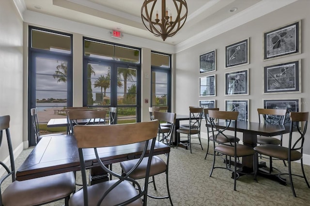 dining area with an inviting chandelier, a raised ceiling, and crown molding