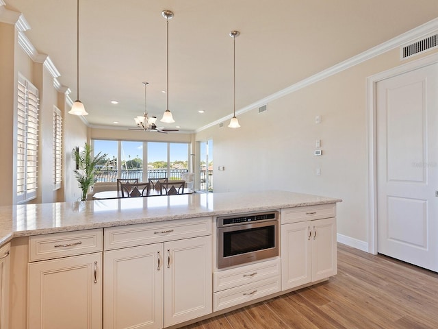 kitchen with pendant lighting, light wood-type flooring, crown molding, oven, and a notable chandelier