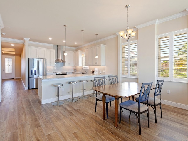 dining room with a notable chandelier, sink, light wood-type flooring, and ornamental molding