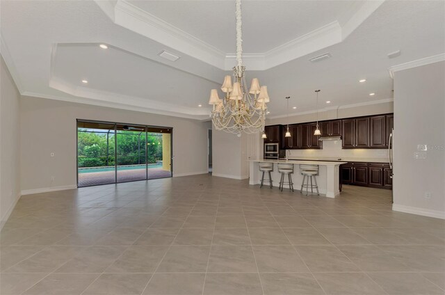 unfurnished living room featuring a tray ceiling, a chandelier, light tile patterned floors, and crown molding