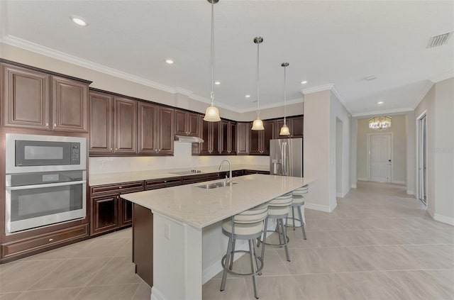 kitchen featuring light stone counters, sink, a center island with sink, decorative light fixtures, and appliances with stainless steel finishes