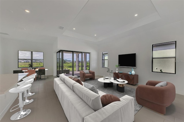 living room featuring a tray ceiling and tile patterned floors