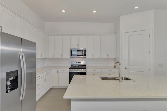 kitchen with white cabinets, a center island with sink, appliances with stainless steel finishes, and sink