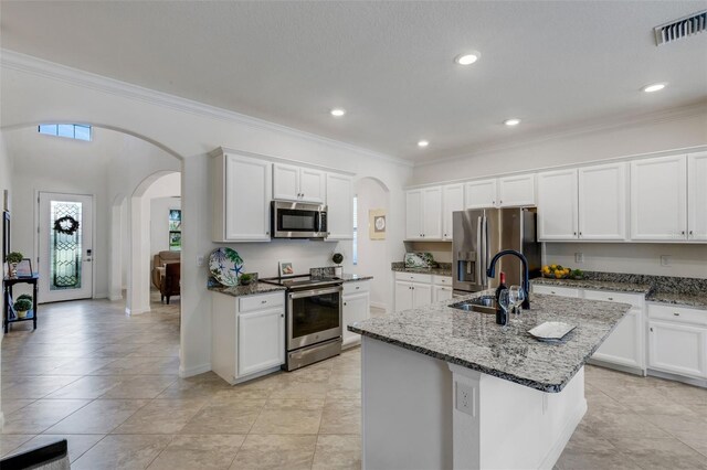 kitchen featuring an island with sink, ornamental molding, sink, white cabinetry, and stainless steel appliances