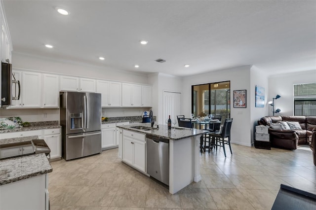 kitchen with appliances with stainless steel finishes, sink, dark stone counters, and white cabinetry