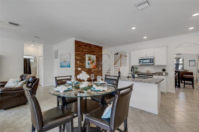 tiled dining area featuring ornamental molding and sink