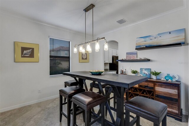 dining space with crown molding and light tile patterned flooring